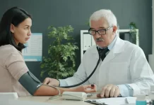 Badania profilaktyczne dla osób pracujących przy komputerze – jakie diagnostyki warto wykonać? Lekarz mierzy ciśnienie młodej kobiecie w nowoczesnym gabinecie.