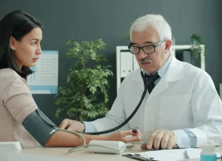Lekarz mierzy ciśnienie młodej kobiecie w nowoczesnym gabinecie.